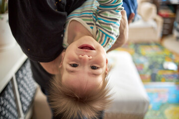 Little boy cute child  baby playing with his father, hanging upside down. Toddler having fun at home. Happy childhood, family love concept