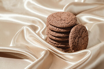 Brown american cookies on beige silk fabric background. Minimal style. Bakery and pastry concept.
