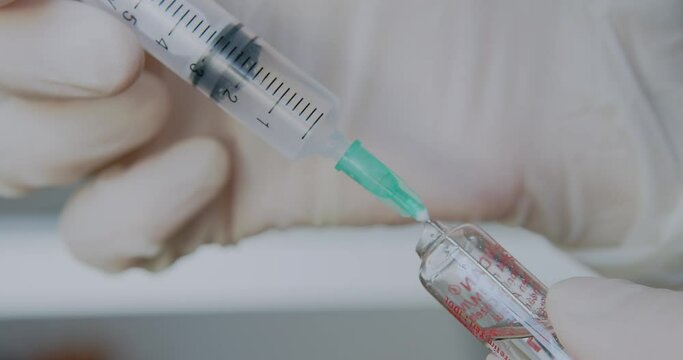 The doctor dials an antibiotic from a glass ampoule into the syringe. Macro shooting. Needle syringe with medicine. Antibiotic injections. High quality 4k footage