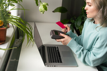 Young woman holding credit card and using laptop computer. Businesswoman or entrepreneur working at home. Online shopping, e-commerce, internet banking, spending money, working from home concept.