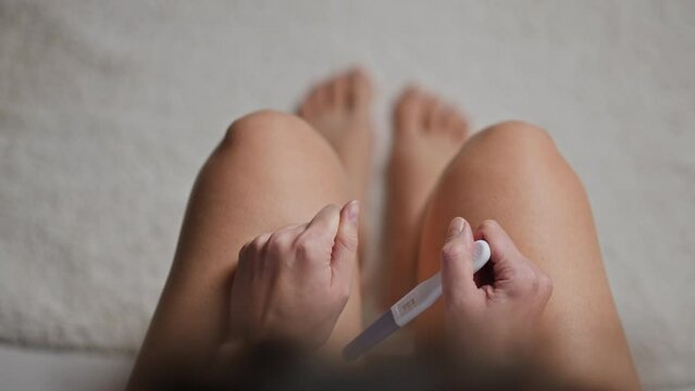Close up of hands, Pregnant woman sits Stressfully Conducts home pregnancy test In frequent toilet, Pregnant woman concept Sitting on toilet for pregnancy test in clinic, Test kit
