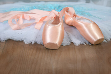 Ballet beige pointe shoes with a ribbon on the tutu skirt. Ballerina set.
The concept of dance, spring, ballet school, ballerinas clothes and things.
