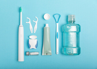 Toothbrush,electric toothbrush,tongue cleaner, floss, toothpaste tube and mouthwash on blue...