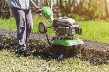 Farmer man plows the land with a cultivator preparing the soil for sowing