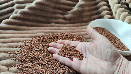 Brown buckwheat groats and hand of woman in it. Food for background and texture. Product and food...
