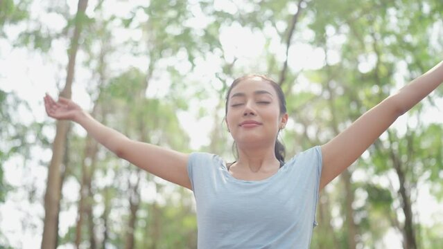 young Asian woman person breath a nature fresh air, relax and freedom lifestyle to happy in green park beautiful girl at summer travel and enjoy vacation with a tree outside for health careful