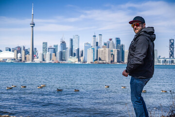 man poses on the coast of toronto island park with toronto skyline on background