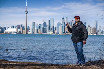 man poses on the coast of toronto island park with toronto skyline on background