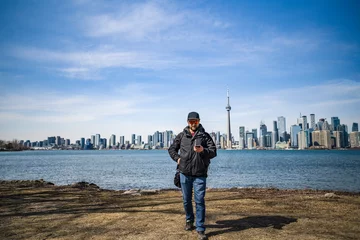 Foto op Canvas man poses on the coast of toronto island park with toronto skyline on background © Sid Smith