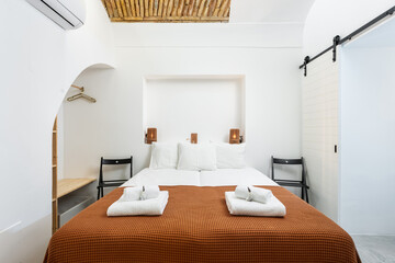 Traditional modern Iberian bedroom with brick ceiling and clean towels and linens. front view