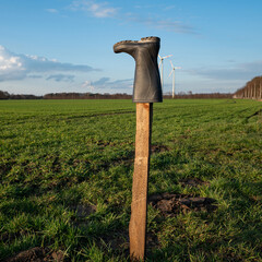 Gummistiefel auf einem Holzpfahl von Landwirten an einem Feld aufgestellt als Mahnmahl für das...