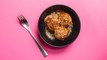 Delicious profiteroles with chocolate on a dark plate.