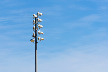 Stadium lights on a tower pole with a blue sky