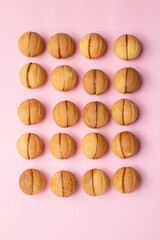 Walnut-shaped cookies with boiled condensed milk on a pale pink background. Mocap.
