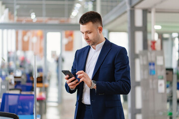 a man in a blue business suit with a phone in hand in the coworking office. 