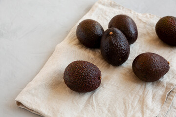 Raw Organic Hass Avocados on a gray background, side view.