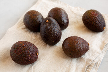 Raw Organic Hass Avocados on a gray background, side view.