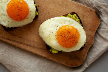 Homemade Avocado Toast with Eggs on a rustic wooden board, top view. Flat lay, overhead, from above.