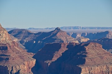 Bright desert sunlight shines down on the Grand Canyon, casting shadows on every crease and layer of the eroded canyon carved over many years by the Colorado River thousands of feet below