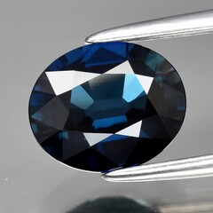 Natural gemstone blue sapphire on gray background