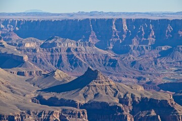 Bright desert sunlight shines down on the Grand Canyon, casting shadows on every crease and layer...
