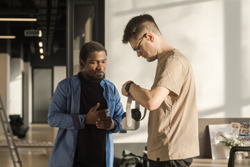 Obraz premium Colleague helps put on vr headset. Testing metaverse world, touching virtual reality subjects. IT Development Team Working on VR Project. Abstract cyber world in office