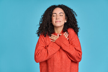 Young adult smiling latin woman, happy pretty curly female model holding hands on chest expressing...