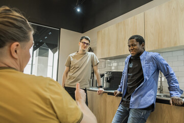 Group of cheerful young people talking and smiling during coffee break time in the office. Team of...