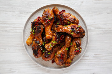 Homemade Easy Sticky Chicken Drumsticks on a Plate on a white wooden background, top view. Overhead, from above, flat lay.