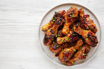 Homemade Easy Sticky Chicken Drumsticks on a Plate on a white wooden background, top view. Overhead, from above, flat lay. Copy space.