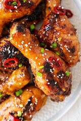 Homemade Easy Sticky Chicken Drumsticks on a Plate on a white wooden background, top view. Overhead, from above, flat lay. Close-up.