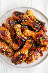 Homemade Easy Sticky Chicken Drumsticks on a Plate on a white wooden background, top view. Overhead, from above, flat lay. Close-up.