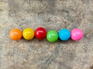 Top view inline of multicolor plastic balls on cement texture background. Many colorful plastic...