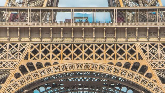 Champ de Mars and the bottom part of Eiffel Tower timelapse in a sunny summer day. Paris, France. Green trees and cloudy sky, people sitting and walking around