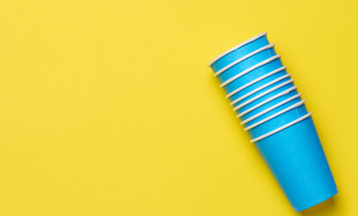 Disposable paper cups on yellow background, top view