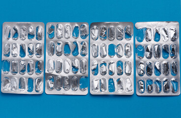 Empty blister pack of capsules on a blue background, close up - obrazy, fototapety, plakaty