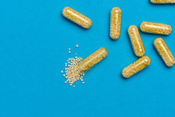 Transparent medical capsules with yellow granules inside on a blue background, tablets for...