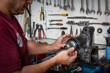 Mecánico reparando un repuesto de automovil en su taller