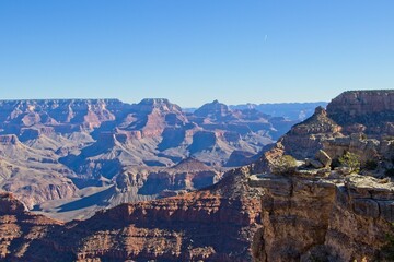 Bright desert sunlight shines down on the Grand Canyon, casting shadows on every crease and layer of the eroded canyon carved over many years by the Colorado River thousands of feet below