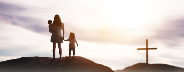 a beautiful family in a sunset on a background with the cross of christ - god hopelessness help concept