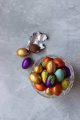 Chocolate eggs wrapped in a foil top view photo. Still life with Easter sweets on a table. 