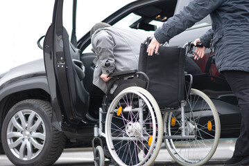 Obraz premium A woman helps aphysical disabled person to get into the car