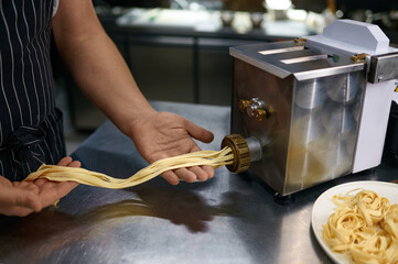 Closeup chef using pasta maker on restaurant kitchen