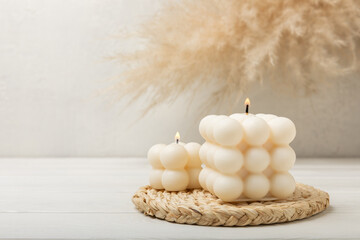 Fototapeta na wymiar Soy wax candle on a textured table. Interior decor with a handmade burning candle. Hygge home decoration concept and aromatherapy. Bubble candle on the background of a textured wall.Place for text.