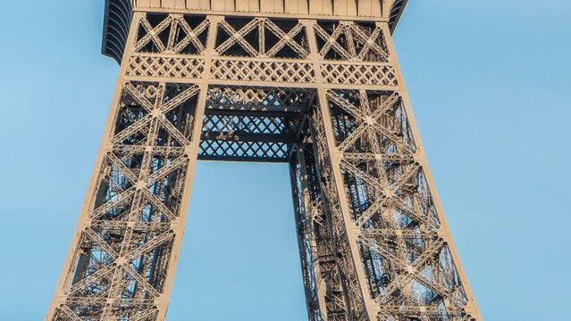 Close up view of the first section of the Eiffel Tower with tourists on observation deck timelapse in Paris, France. Sunny summer day with blue clody sky