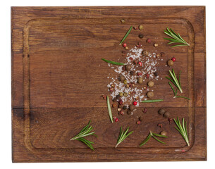 Twigs and leaves of rosemary, dry fruits of red, black and allspice and salt on a wooden cutting board, top view