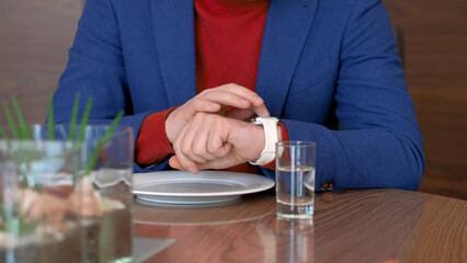 Fototapeta na wymiar Man using mobile app in smart watch on hand while waiting food in cafe