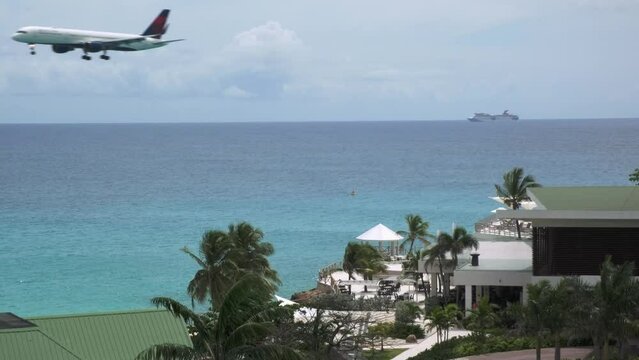 Aircraft on final approach before land to Sint Maarten airport flies low above coastal area and roof hotel