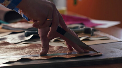 Skinner is marking and taking metal ruler and knife for cutting