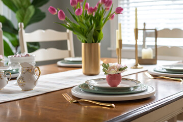 Closeup of stylish spring table setting with pink tulips in a gold vase - 583702989